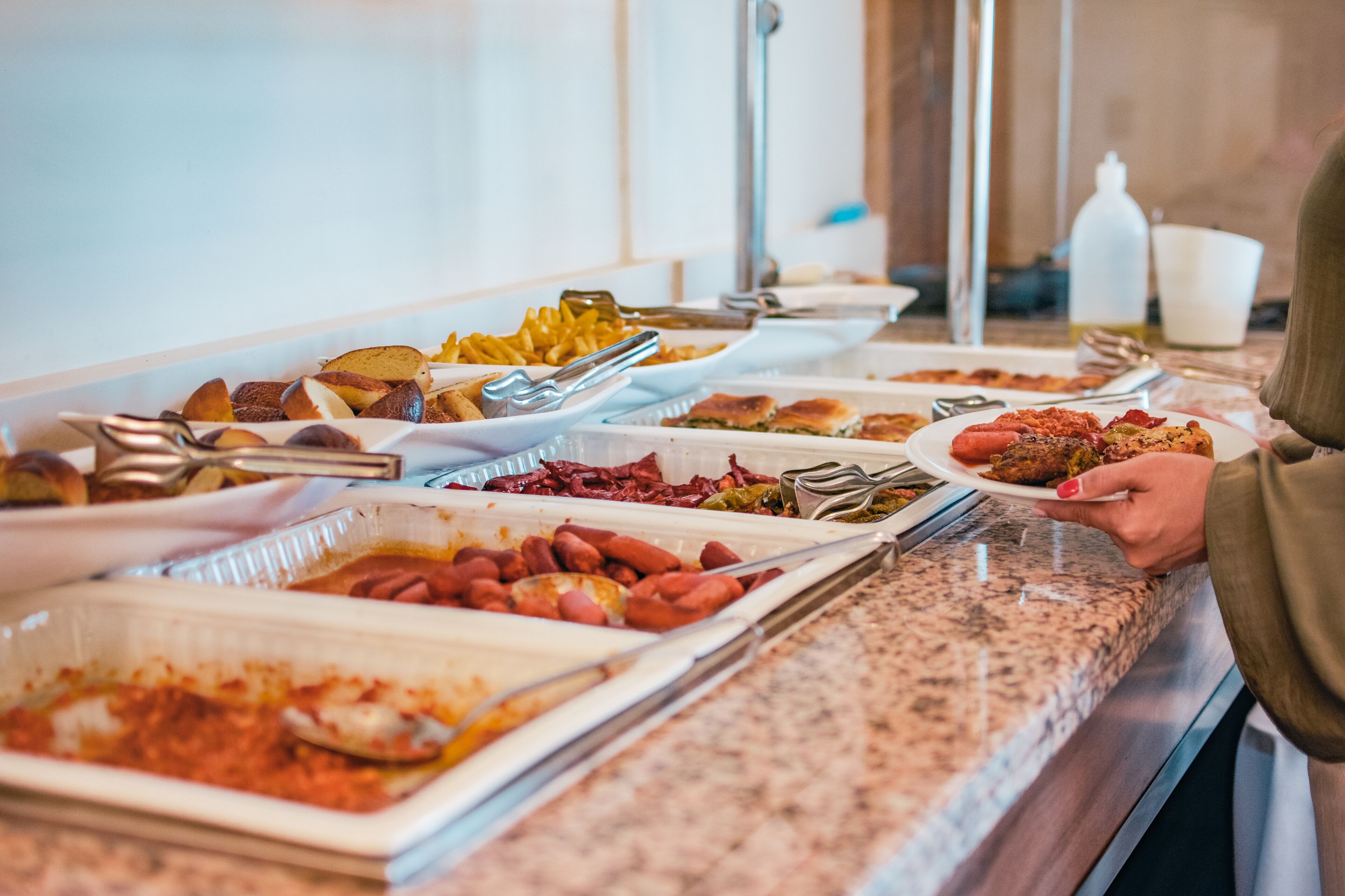 A buffet with various dishes including pasta, bread, and hot dogs.