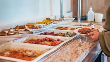 A buffet with various dishes including pasta, bread, and hot dogs.