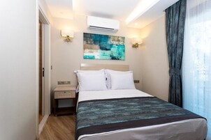 Quarto de hotel com cama, mesas de cabeceira, ar condicionado e um quadro na parede.