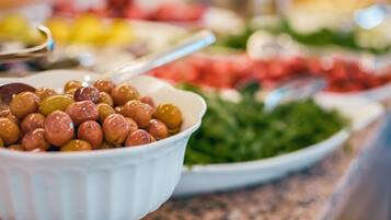 Un bufé con diversos platos, incluyendo un bol de aceitunas y una bandeja de verduras.