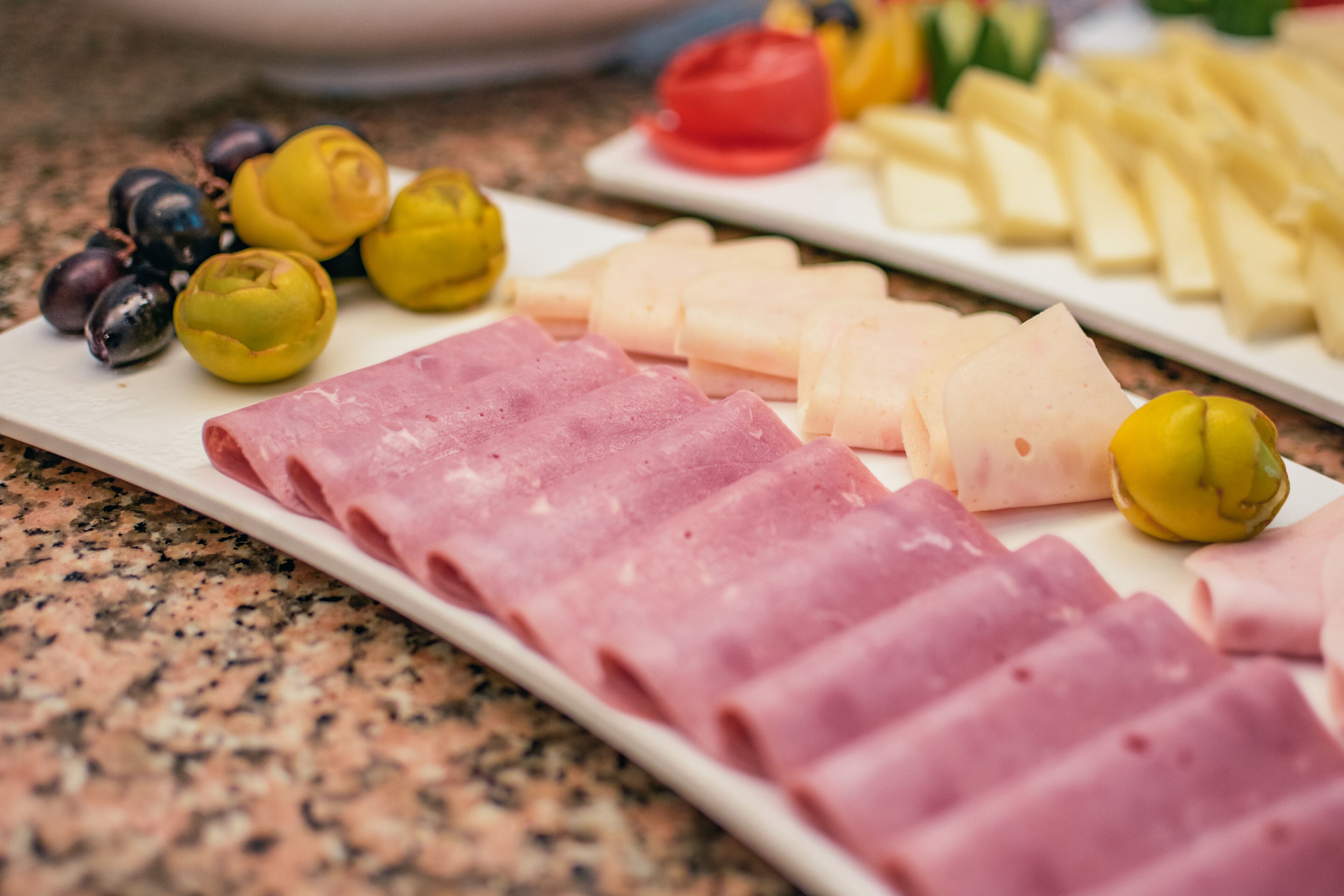 Una tabla de fiambres con diversos embutidos, quesos y aceitunas.
