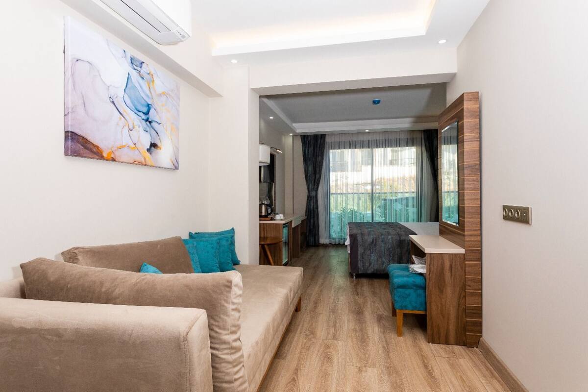 Een moderne woonkamer met een bank, een bureau en een groot raam.