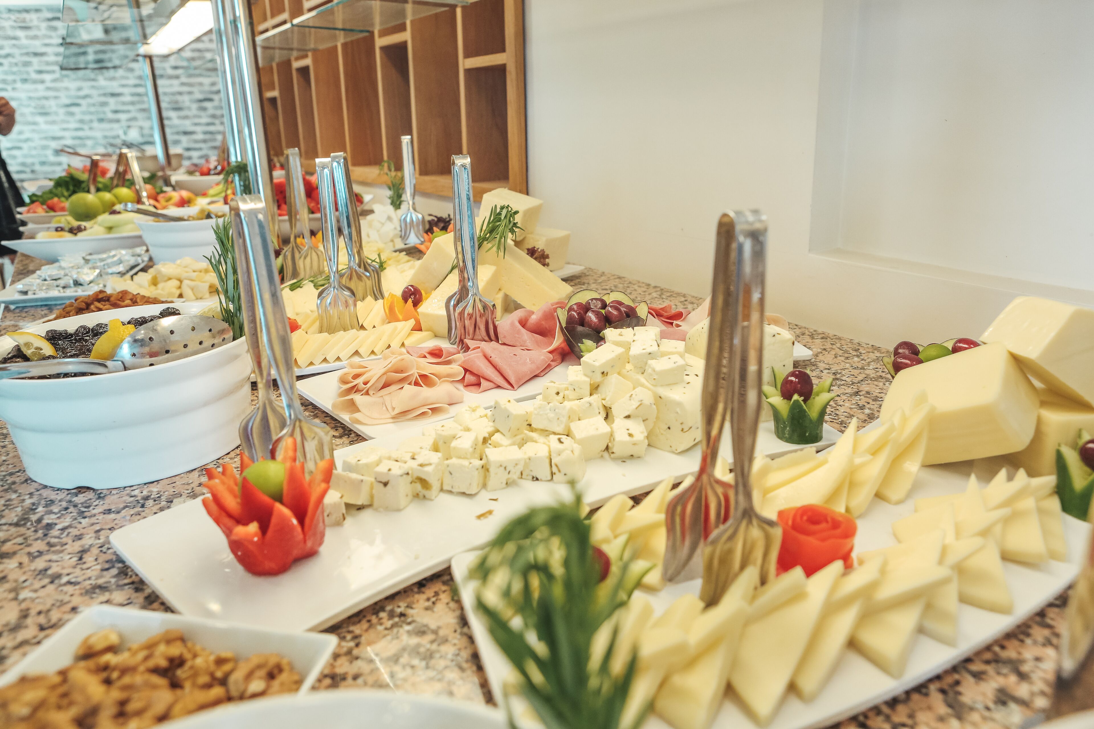 Ein Buffet mit verschiedenen Käsesorten, Früchten und Nüssen auf einer Marmorplatte.