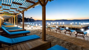 Een strandlounge met houten terraszitplaatsen en uitzicht op zee.