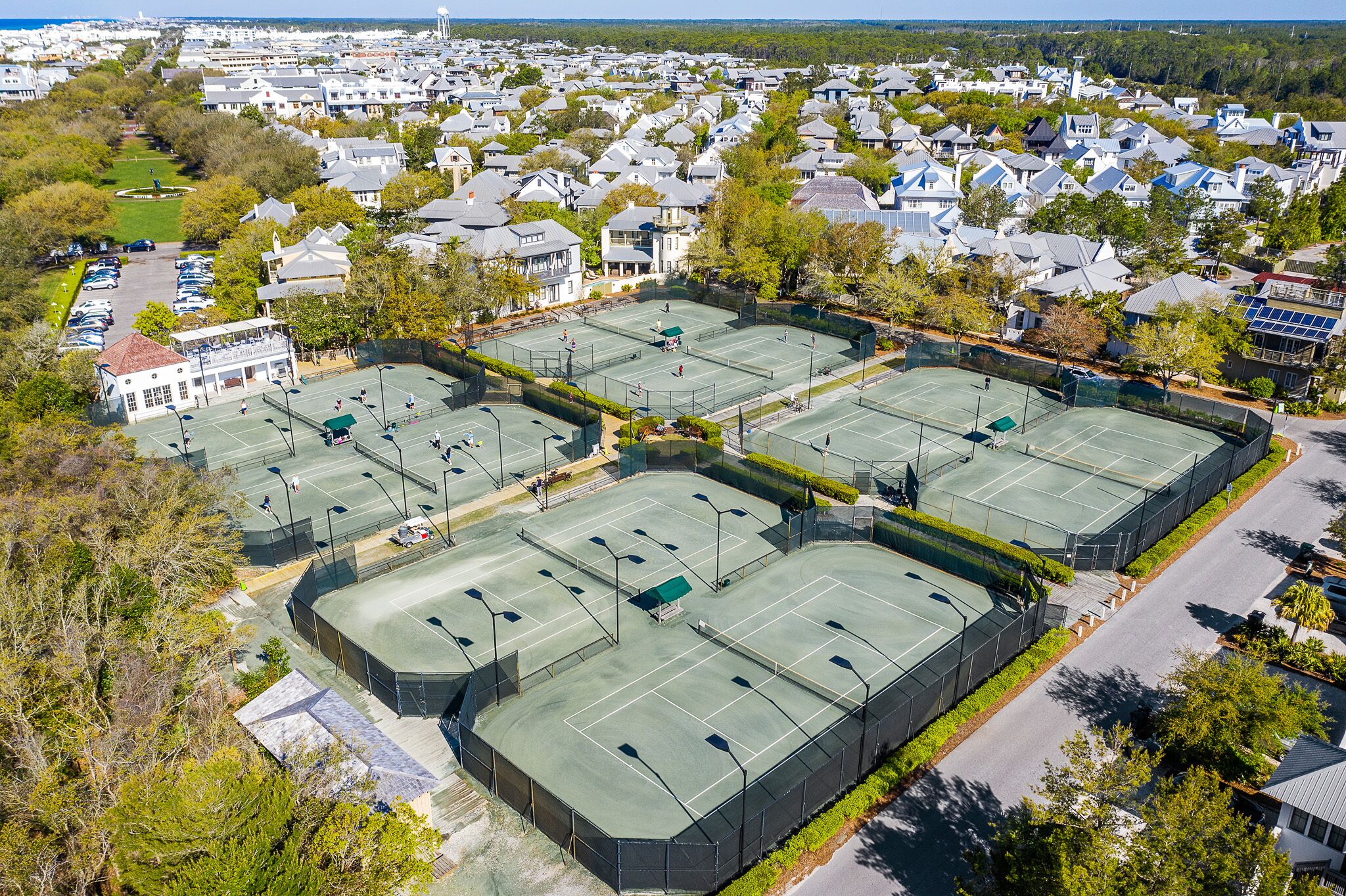 An aerial view of a residential area with multiple tennis courts surrounded by houses.