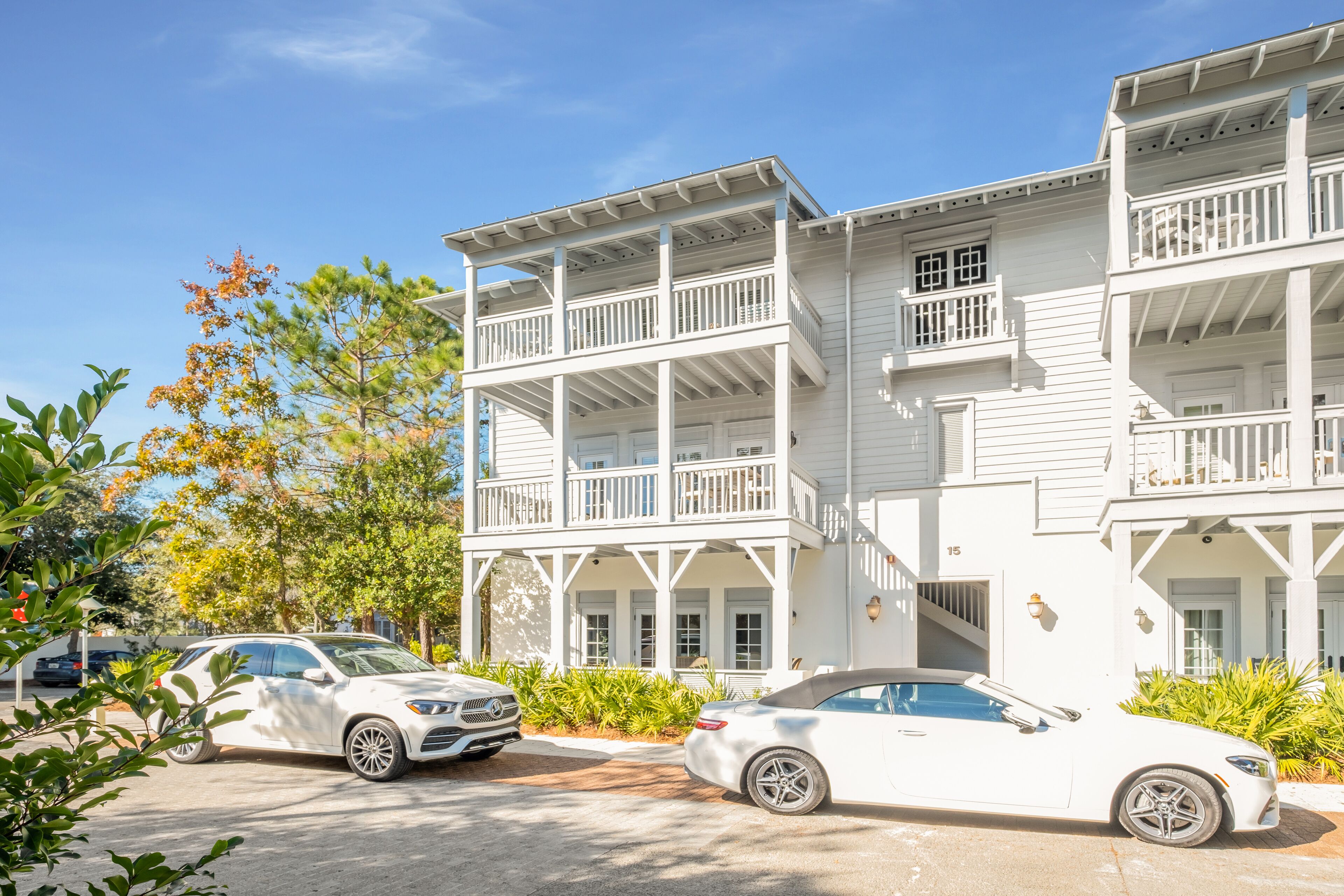 Un bâtiment blanc à deux étages, doté de balcons, d’un porche avant couvert et d’un garage.
