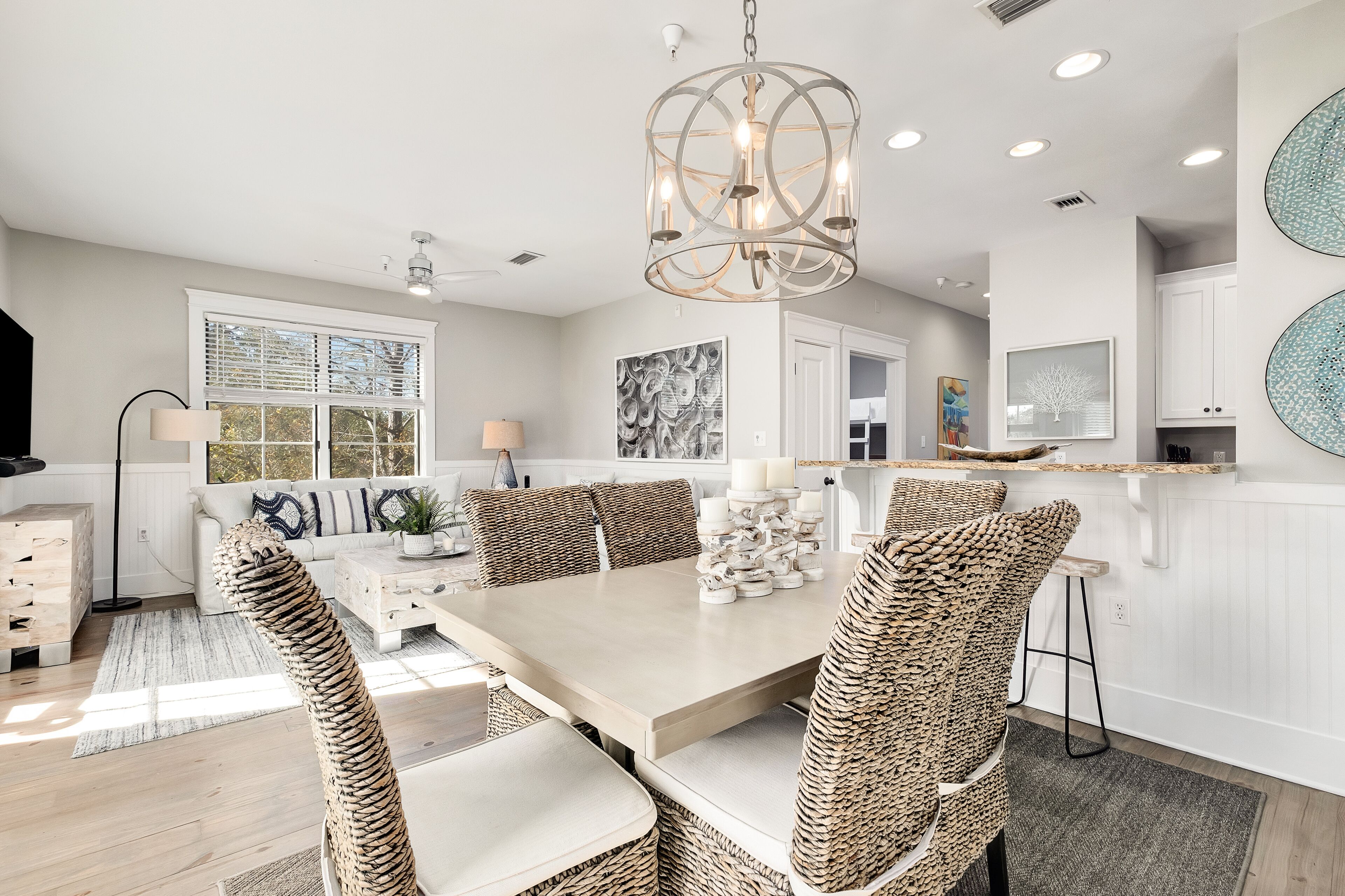 A modern kitchen with a large island, white cabinetry, and a chandelier.