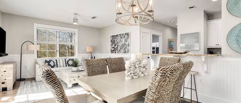 A modern kitchen with a large island, white cabinetry, and a chandelier.
