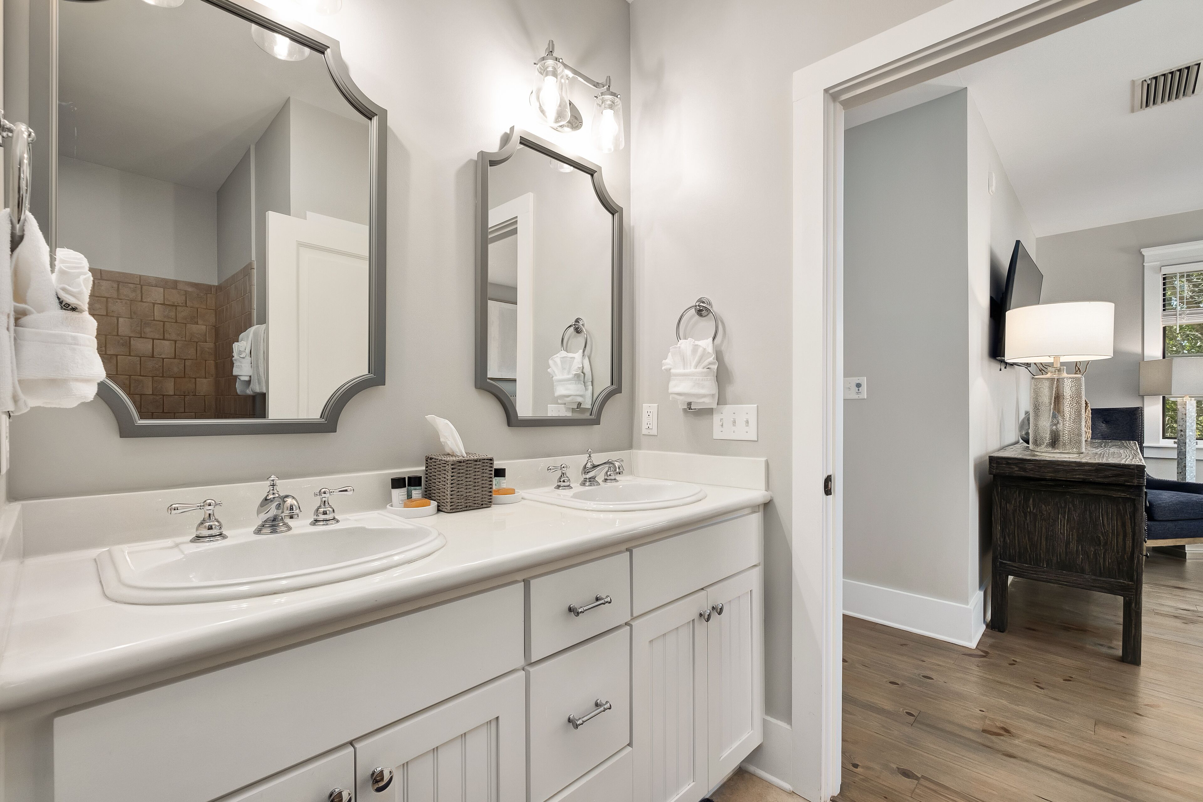 A modern bathroom with dual sinks, a large mirror, and a vanity with drawers.