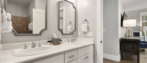 A modern bathroom with dual sinks, a large mirror, and a vanity with drawers.