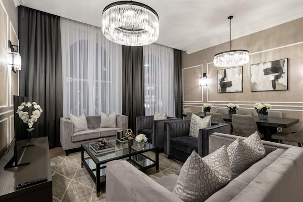 A modern living room with a sofa, armchairs, a coffee table, and a chandelier.