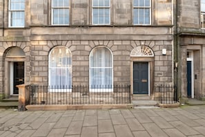 A historic building with arched windows, a black iron fence, and a blue door. - Luxury Georgian City Retreat - Hot Tub - Patio (Edinburgh)
