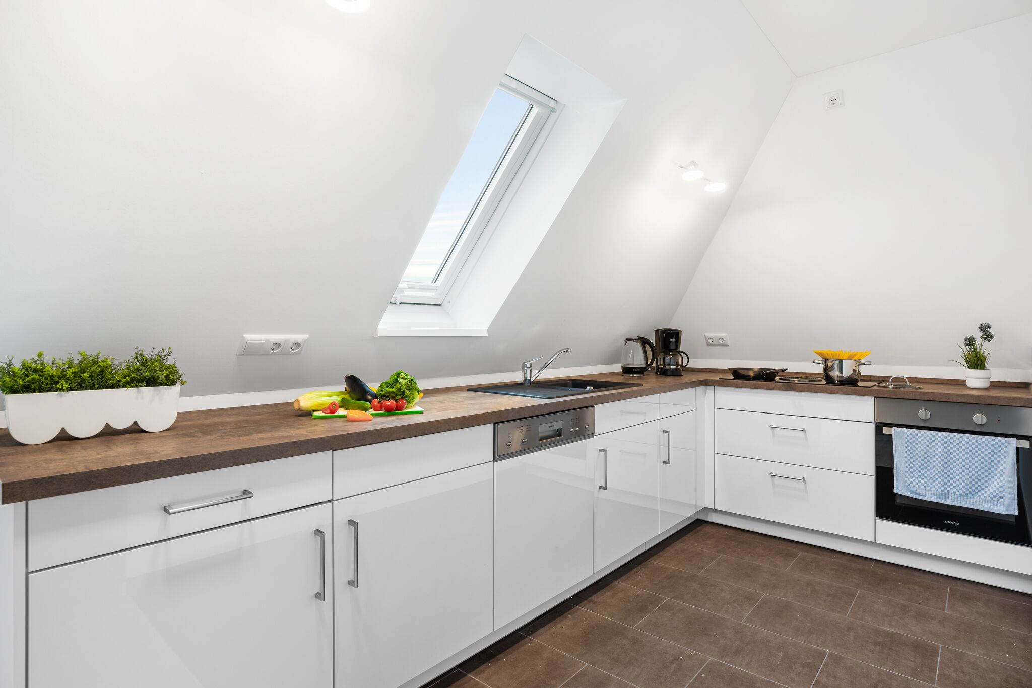 Una cucina moderna con mobili bianchi, un piano di lavoro in legno, un lucernario e un forno integrato.