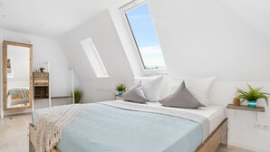 Una camera da letto moderna con un lucernario, un letto con una coperta azzurra e una testiera in legno.