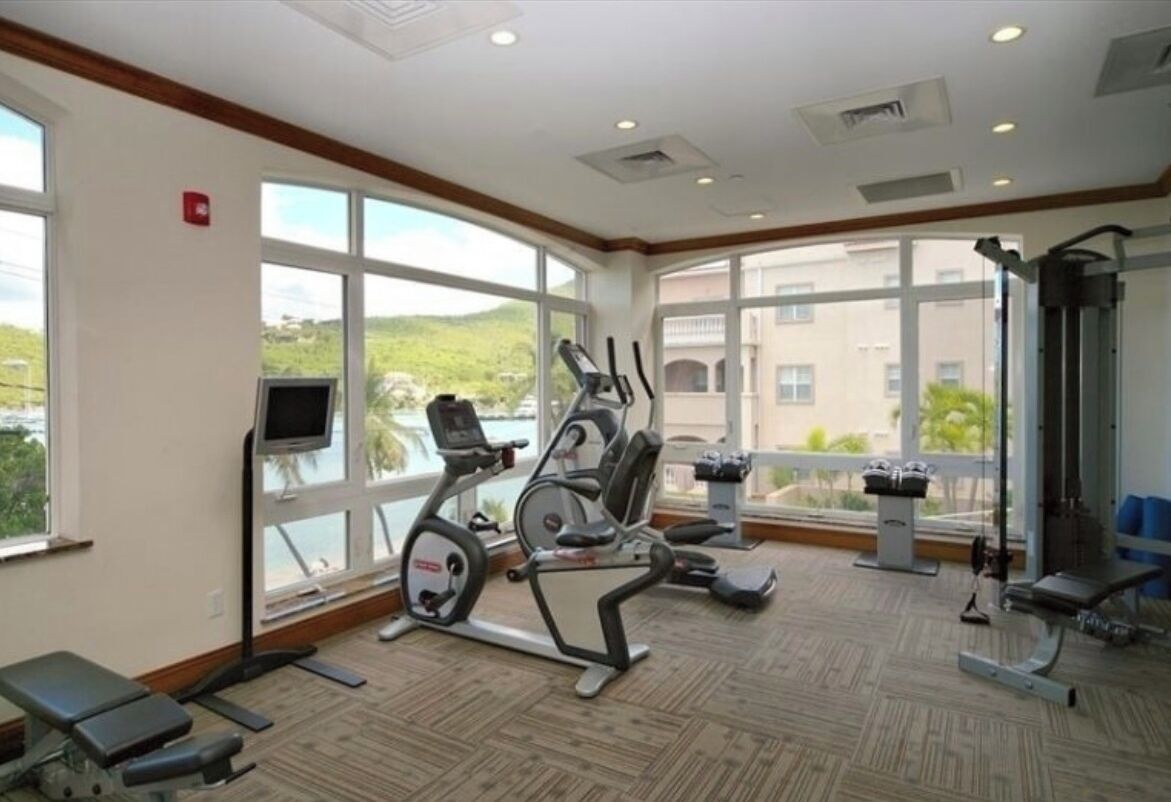 A gym with exercise equipment, large windows, and a view of the outdoors.