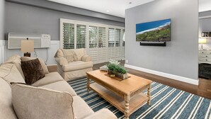 A modern living room with a beige sofa, a wooden coffee table, and a large window with blinds. - Condo on property at LaCosta Golf Resort & Spa 689 (Carlsbad)