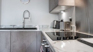 A modern kitchen with a stainless steel sink, a built-in stovetop, and a toaster. - Modern 2 Bedroom Riverside Apartment in Leeds (Leeds)