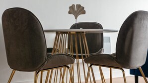 A dining area with a round table and four chairs with gold legs. - Modern 2 Bedroom Riverside Apartment in Leeds (Leeds)