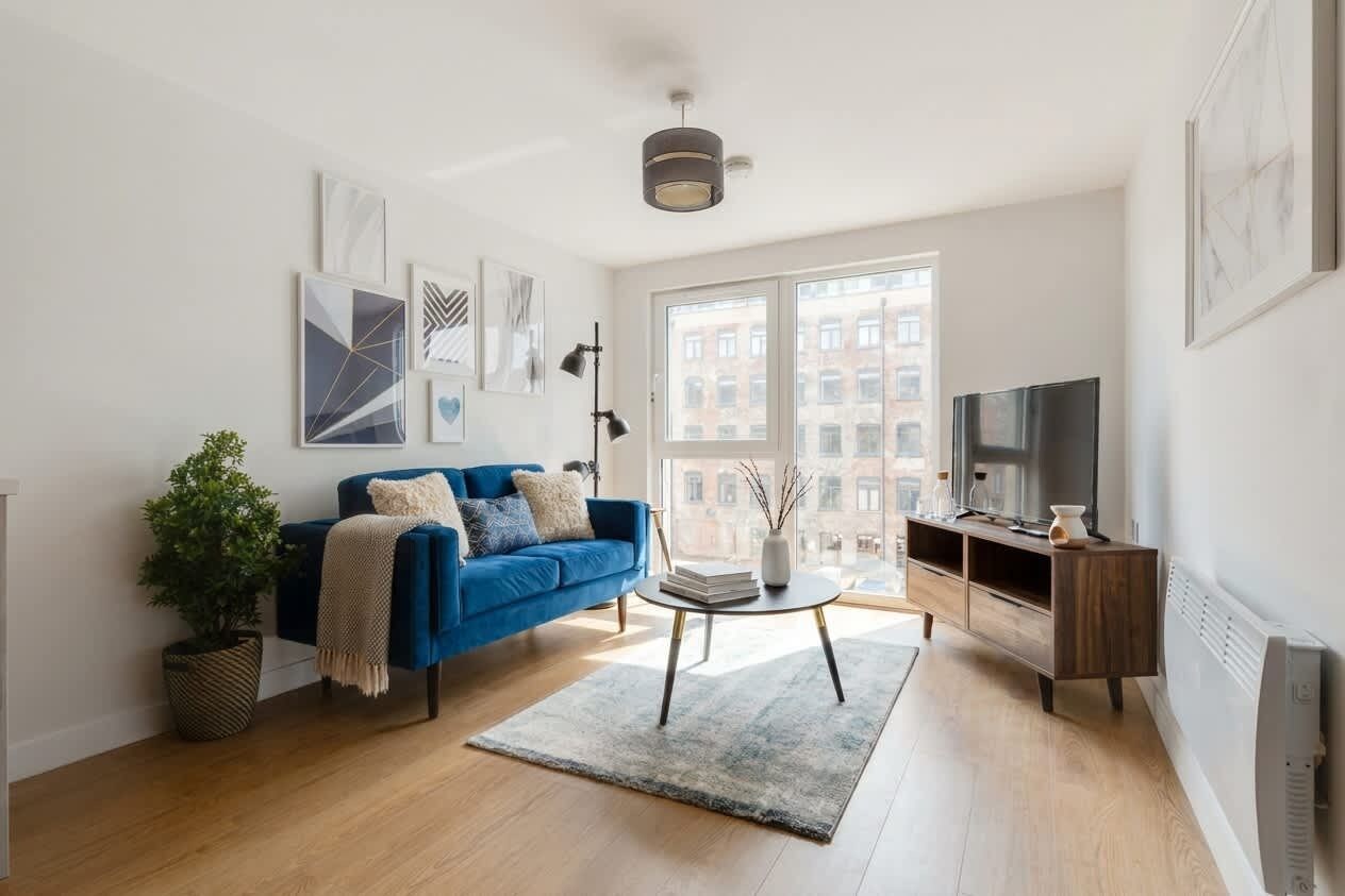 Un salon moderne avec un canapé bleu, une table basse et un téléviseur posé sur un meuble en bois.
