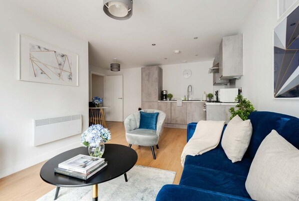 A modern living room with a blue sofa, a round coffee table, and a grey armchair.
