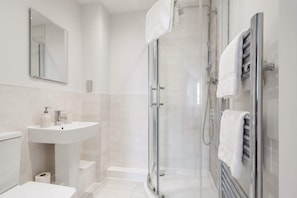 A modern bathroom with a glass-enclosed shower, a white sink, and a mirror.