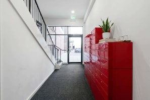 Um corredor com escadas, um armário vermelho e um vaso de plantas.