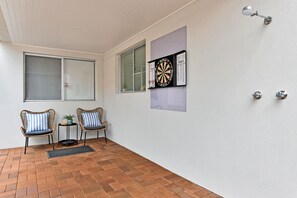 A room with two wicker chairs, a dartboard, and a window. - Reflections at Sunset Beach (Soldiers Point)