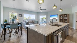 A spacious kitchen with a large island, modern pendant lighting, and a view of the outdoors. - Casa Caribe-Soundside Private Home w/Pool and Tennis 2 Min from the Beach (Navarre)