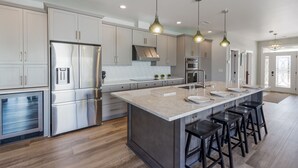 A modern kitchen with stainless steel appliances, a central island with bar stools, and pendant lighting. - Casa Caribe-Soundside Private Home w/Pool and Tennis 2 Min from the Beach (Navarre)