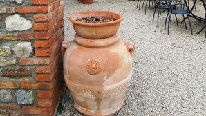 A courtyard with terracotta pots, a brick wall, and a tiled roof. - Villa Cenerentola (Trequanda)