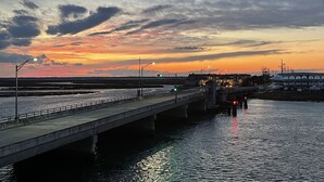 A bridge over water with streetlights and buildings in the background.