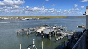 A marina with boats docked, a pier, and a grassy landscape in the background.