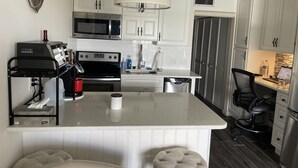 A modern kitchen with white cabinetry, a central island, a microwave, a stove, and a refrigerator.