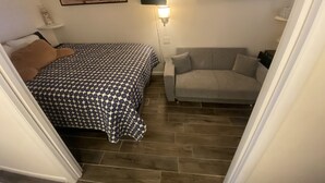 A bedroom with a bed, a sofa, and two framed pictures on the wall.