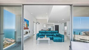 Ein modernes Wohnzimmer mit einem türkisfarbenen Sofa, einem weißen Couchtisch und einem Gemälde an der Wand.