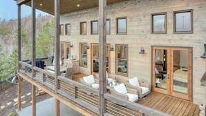 Een houten chalet met terras, zitgedeelte buiten en grote ramen.