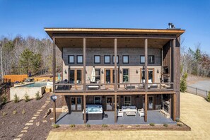 A multi-story building with a deck, outdoor seating, and a hot tub. - Water's Edge 2 - Private pool & mountain views (Mineral Bluff)