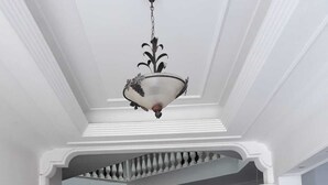 Una gran escalera conduce a una habitación con candelabro, sillas rojas y piso de madera.