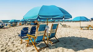 A beach with multiple blue umbrellas and lounge chairs, some labeled 'Azure'. - Azure 223 | 3BR Coastline View | FREE Beach Service (Fort Walton Beach)