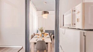 A modern dining area with a long table, chairs, and a hanging light fixture. - Sweett | Rocafort Principal 1 (Barcelona)