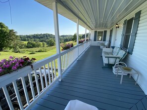 A covered porch with a view of a green landscape, white railings, and outdoor seating. - Sunnyside Country Retreat - Reunions/Events Farm stay (Amsterdam)