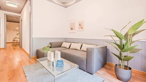 Una sala moderna con un sofá seccional gris, una mesa de centro de vidrio y una planta en maceta.