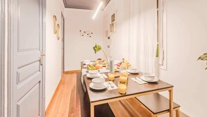 Un comedor con una larga mesa de madera dispuesta para el desayuno, con platos, vasos y diversos alimentos.