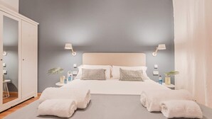 Un dormitorio con cama, dos mesitas de noche, un espejo y dos toallas.