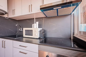 A kitchen with a built-in microwave, a stainless steel range hood, and a window with a view. - Sweett | Rocafort Atic 1 (Barcelona)