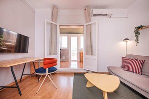 A modern living room with a sofa, a TV, a dining table, and a chair. - Sweett | Rocafort Atic 1 (Barcelona)