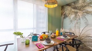 A dining area with a wooden table, chairs, and a tropical mural on the wall. - Sweett | Rocafort Entresuelo 2 (Barcelona)