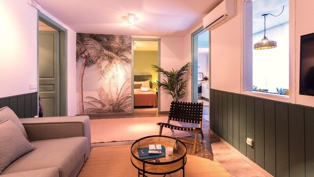 A cozy living room with a sofa, a small round table, a chair, and a large window with a view. - Sweett | Rocafort Entresuelo 2 (Barcelona)