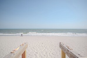 A beach with a wooden structure in the foreground and a person in the distance.