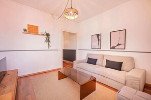 A modern living room with a sofa, coffee table, and a hanging light fixture. - Sweett | Rocafort 504 (Barcelona)